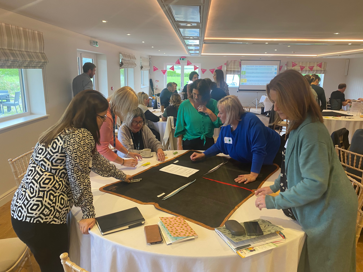 Group of people standing around a table at the PINN forum doing an activity together