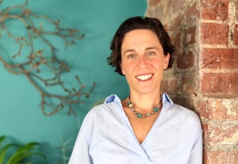 Alex Kelly standing infant of a blue wall